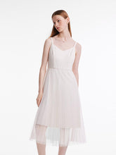A lady wears a white dress with suspenders.